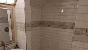 A bathroom with a sink, mirror, and shower area.