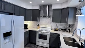 Una cocina moderna con armarios oscuros, un refrigerador blanco, una estufa y un lavamanos.