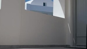 A white building with a clear blue sky visible through an arched window. - Noir Santorini (Santorini)