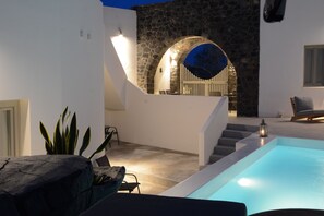 A modern outdoor pool area with a stone wall, a staircase, and a seating area.