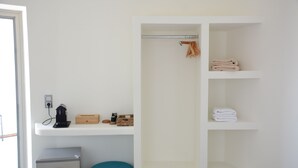 A bathroom with a white vanity, a towel rack, and a small heater on the counter. - Noir Santorini (Santorini)