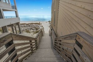 Una escalera de madera que lleva a una playa con vista despejada al océano.