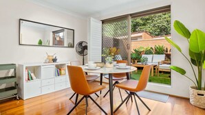 A modern kitchen with a dining area, a large window, and a view of the backyard.