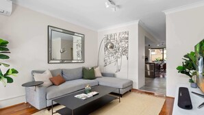 A modern living room with a grey sofa, a black coffee table, and a large mirror on the wall.