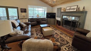 Una sala de estar acogedora con chimenea, sofá de cuero y televisor.