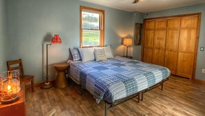 A bedroom with a bed, a ceiling fan, a window, a wooden floor, and a closet. - Large, 4 BR (1 King, 2 Queens), 2 Bath, Recently Renovated (Weedville)