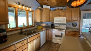 A kitchen with wooden cabinets, a microwave, a stove, and a sink. - Large, 4 BR (1 King, 2 Queens), 2 Bath, Recently Renovated (Weedville)