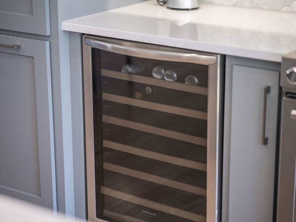 A stainless steel oven with a glass door, located in a kitchen with grey cabinets and a white countertop.