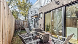 Een terras met Adirondack-stoelen, een vuurkuil en een metselstenen vloer.