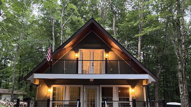 A two-story cabin with a balcony, wooden exterior, and a flag.