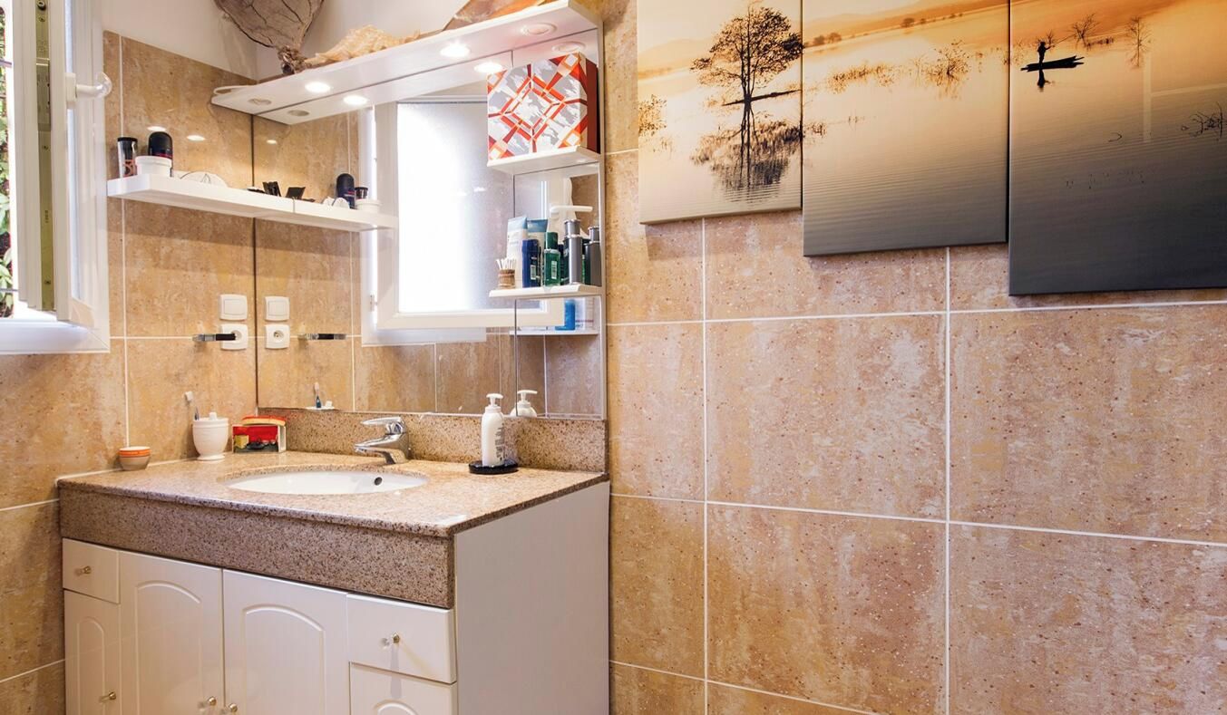 Ein modernes Badezimmer mit einer Granitplatte, weißen Schränken und einem großen Spiegel.