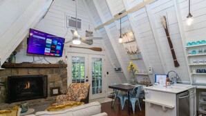 Un espace de vie chaleureux de style loft, doté d’une cheminée, d’un téléviseur et d’un coin repas avec un comptoir de cuisine.