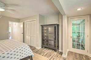 Relax in a spacious bedroom with a large bed, dresser, and balcony offering a view of lush greenery.