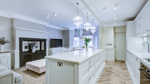 Una cocina moderna con armarios blancos, una isla grande e iluminación colgante.