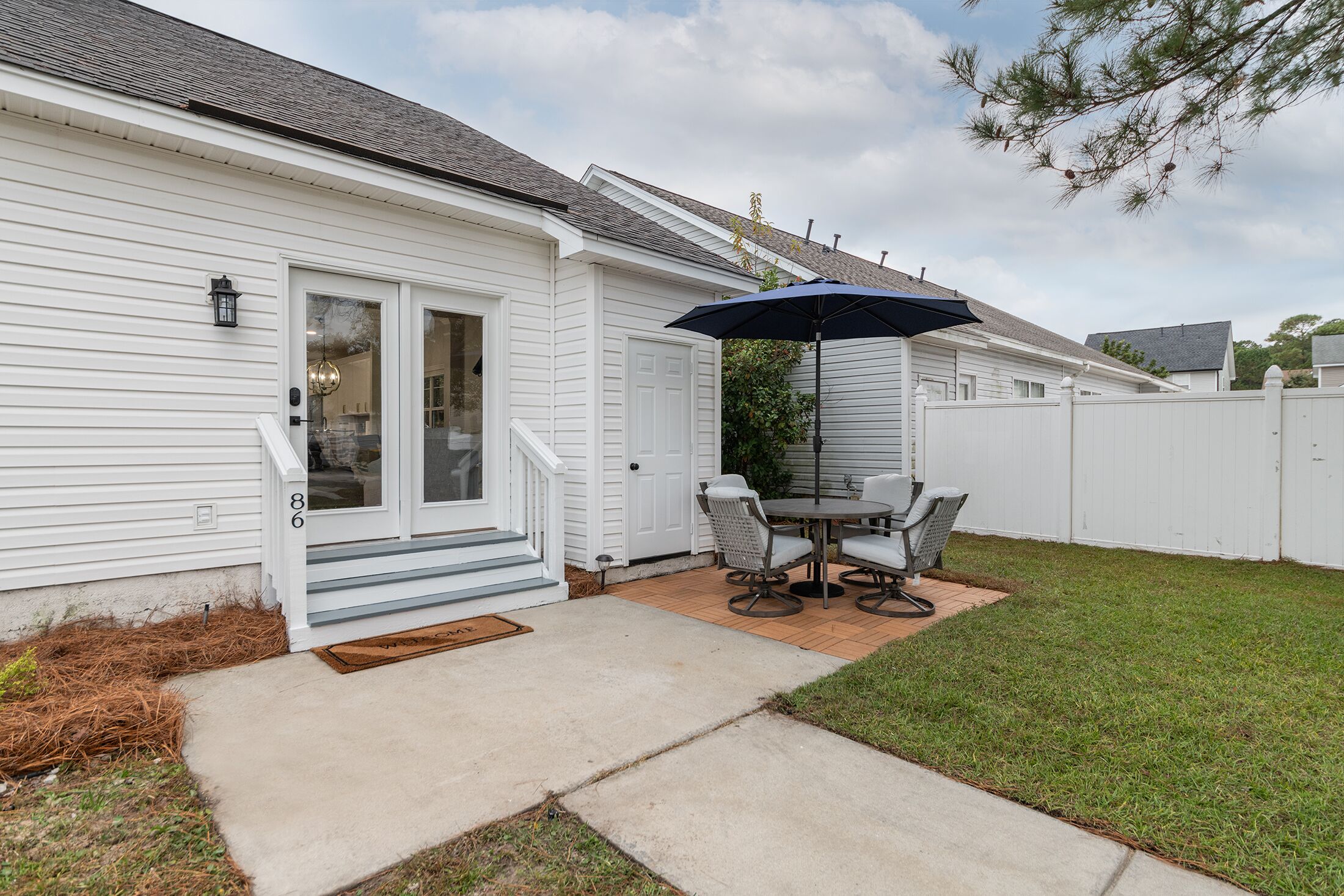 A white house with a covered patio, a dining table, and chairs.