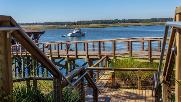 A wooden pier with a boat docked in the background.