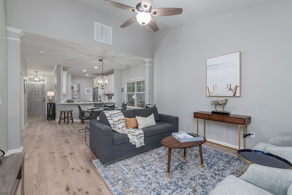 A spacious living area with a gray sofa, a coffee table, and a blue patterned rug.