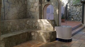 A stone-walled courtyard with a bench and a small fountain. - El Salvador Fustera (Benissa)