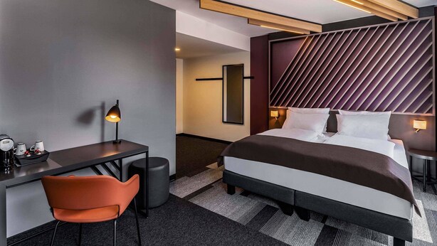 A modern hotel room with a large bed, a desk, and a chair. - B&B Hotel Villingen-Schwenningen (Villingen-Schwenningen)