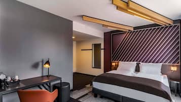 Una habitación de hotel moderna con una cama grande, un escritorio y una silla.
