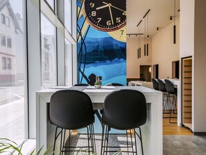 A modern office space with a large wall clock, a long table with chairs, and a view of buildings outside. - B&B Hotel Villingen-Schwenningen (Villingen-Schwenningen)