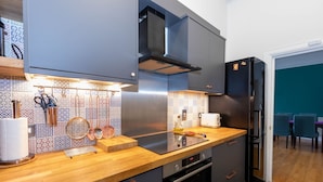 Een moderne keuken met een houten aanrechtblad, roestvrijstalen apparatuur en betegelde backsplash met een patroon.