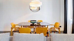 Uma área de refeições com uma mesa redonda, cadeiras amarelas e uma luminária pendente moderna.