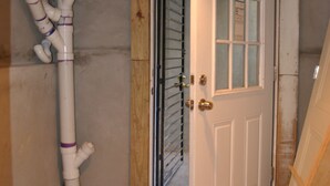 A room with a white door, wooden beams, and visible plumbing. - WALKOUT BASEMENT NEAR downtown  Littleton Ave NEWARK NJ (Newark)