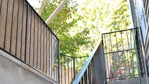 A concrete staircase with black metal railings and a green hose visible at the bottom. - WALKOUT BASEMENT NEAR downtown  Littleton Ave NEWARK NJ (Newark)