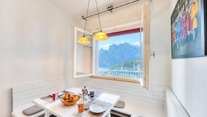 Un comedor con una mesa, sillas, un ventanal con vista a la montaña y un cuadro en la pared.
