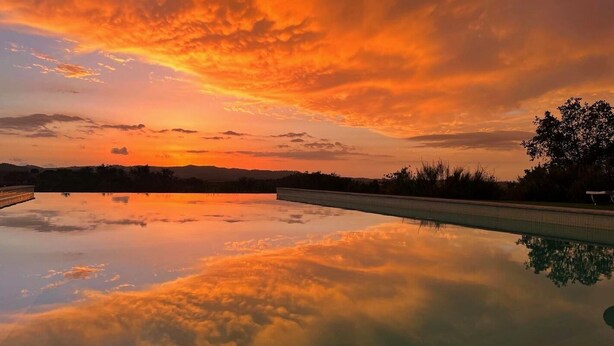 A swimming pool with a clear view of the sky and surrounding landscape during sunset.