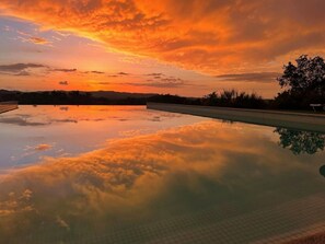 A swimming pool with a clear view of the sky and surrounding landscape during sunset. - Dias Distintos Turismo Rural (Odemira)