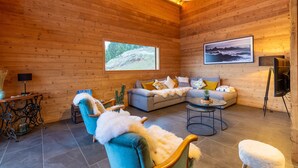 Een gezellig chaletinterieur met een bank, fauteuils, een eettafeltje en een televisie.