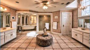 A spacious bathroom with a freestanding bathtub, a ceiling fan, and a large mirror. - Eufaula House (Eufaula)