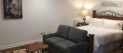 Une chambre à coucher avec un lit, un canapé gris, une petite table et une chaise.