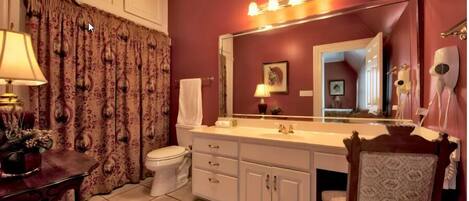 A bathroom with a white vanity, a large mirror, a towel rack, and a hairdryer.