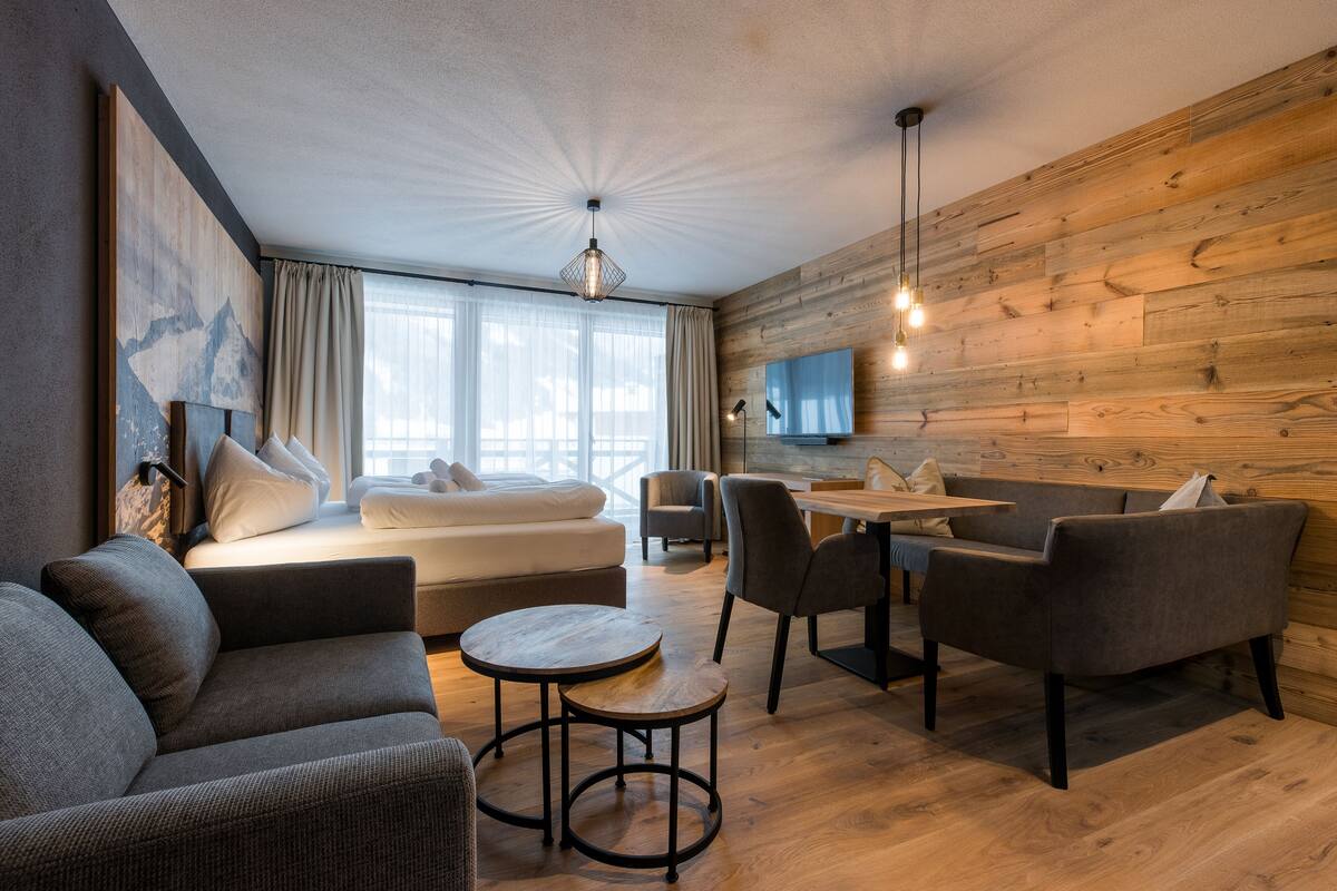 Een moderne woonkamer met een bank, een eettafel en stoelen. Een bed met uitzicht op de omgeving.