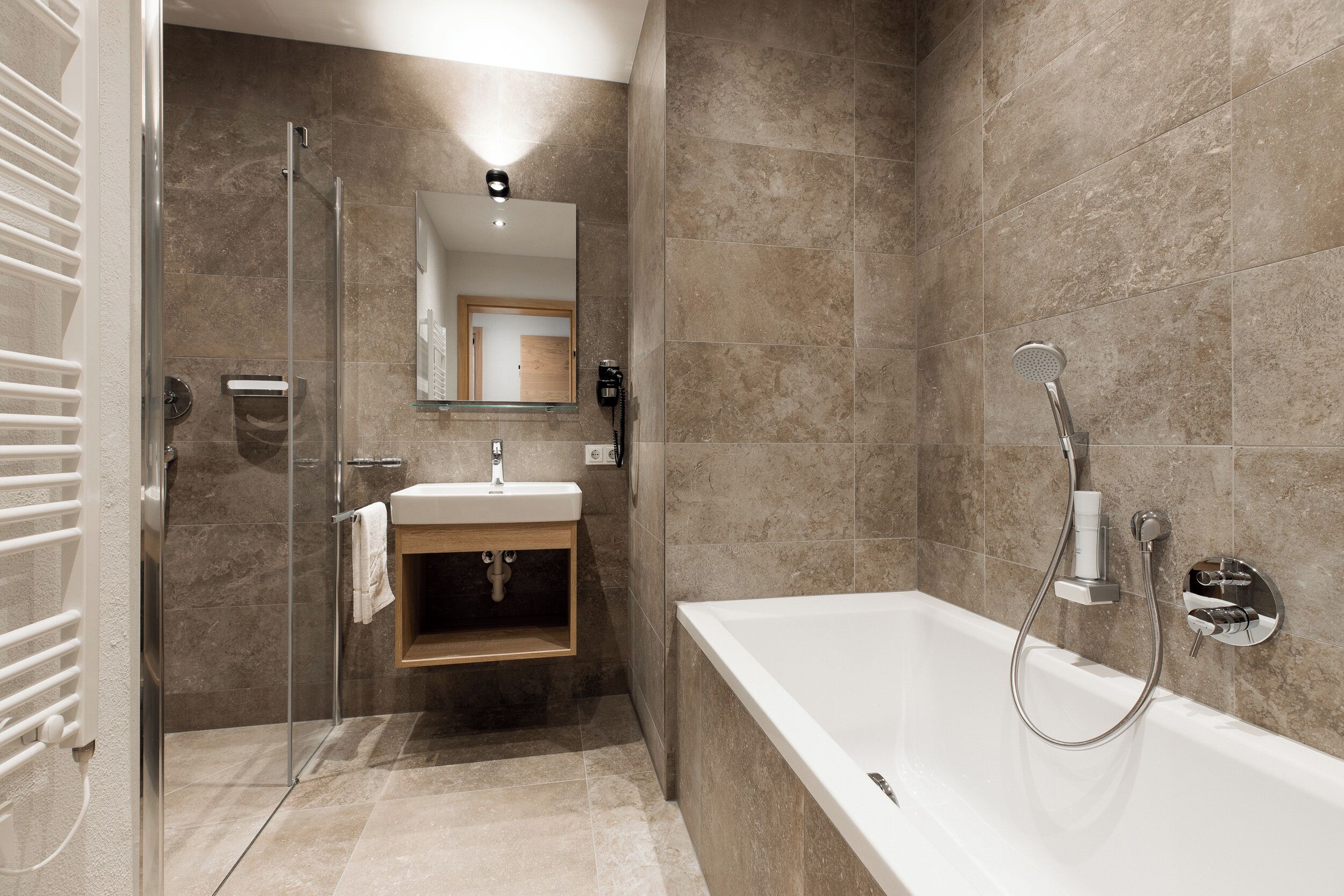 Une salle de bain moderne dotée d’une douche à parois de verre, d’une baignoire sur pieds et d’un meuble-lavabo avec un miroir.