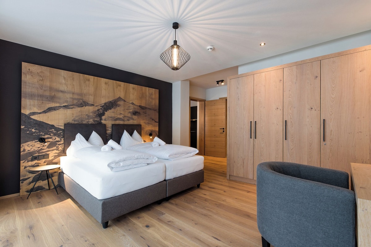 Een moderne slaapkamer met een groot bed, een houten hoofdbord, een kunstwerk aan de muur en inbouwkasten.