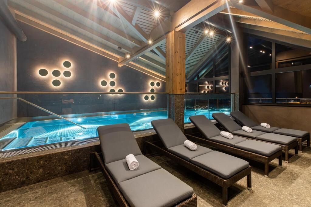 A spa area with a hot tub, lounge chairs, and a modern ceiling design.