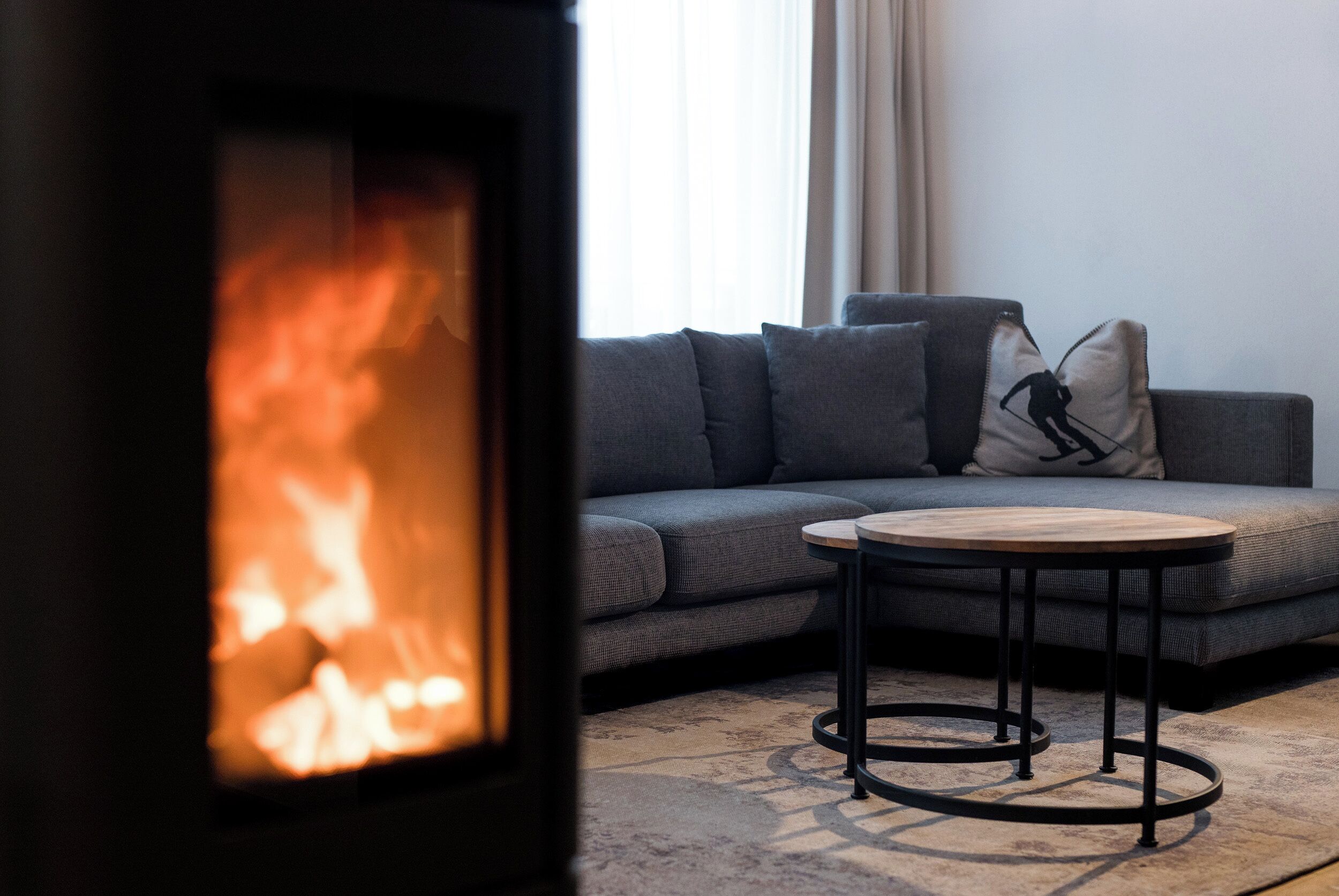 Een moderne woonkamer met een bank, een ronde salontafel en een houtkachel.