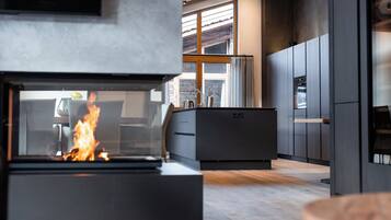 A modern kitchen with a built-in fireplace, wooden cabinets, and a large window.