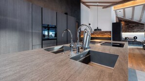 Een moderne keuken met een centraal eiland, roestvrijstalen apparatuur en een steen achterwand.