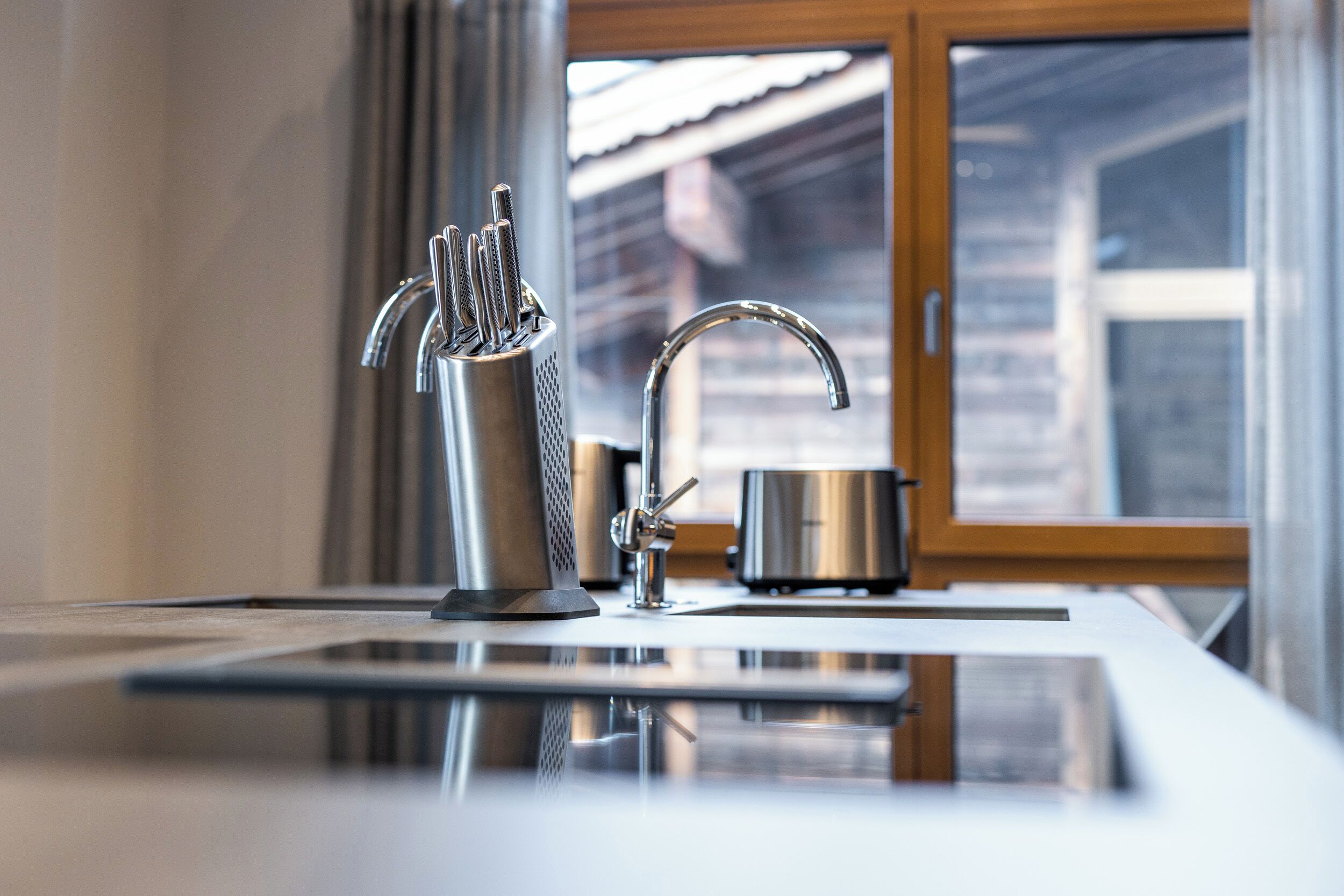 Una cocina moderna con un grifo de acero inoxidable, un portalápices y una olla sobre la encimera.