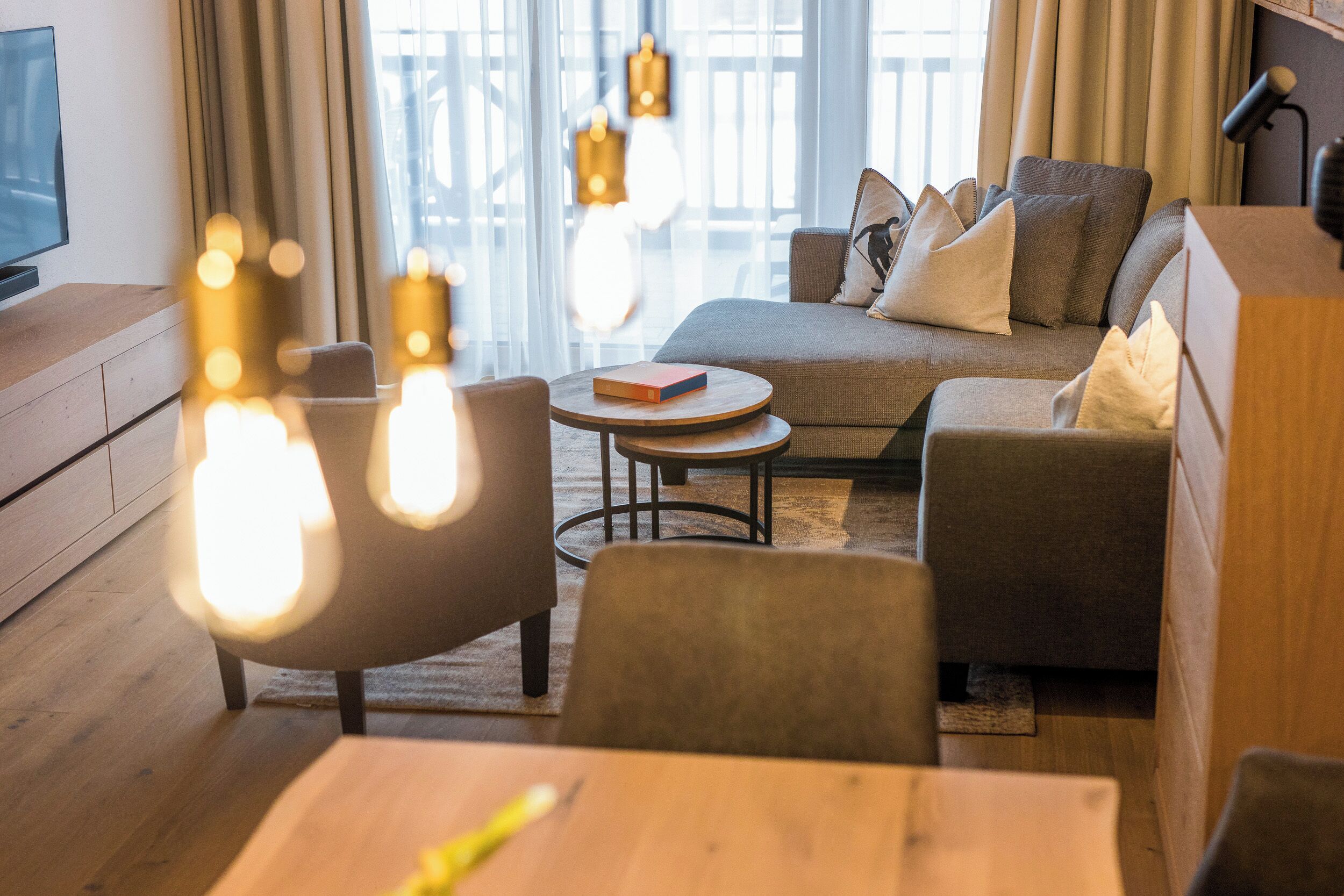A modern living room with a sofa, armchairs, a coffee table, and a TV on a wooden cabinet.