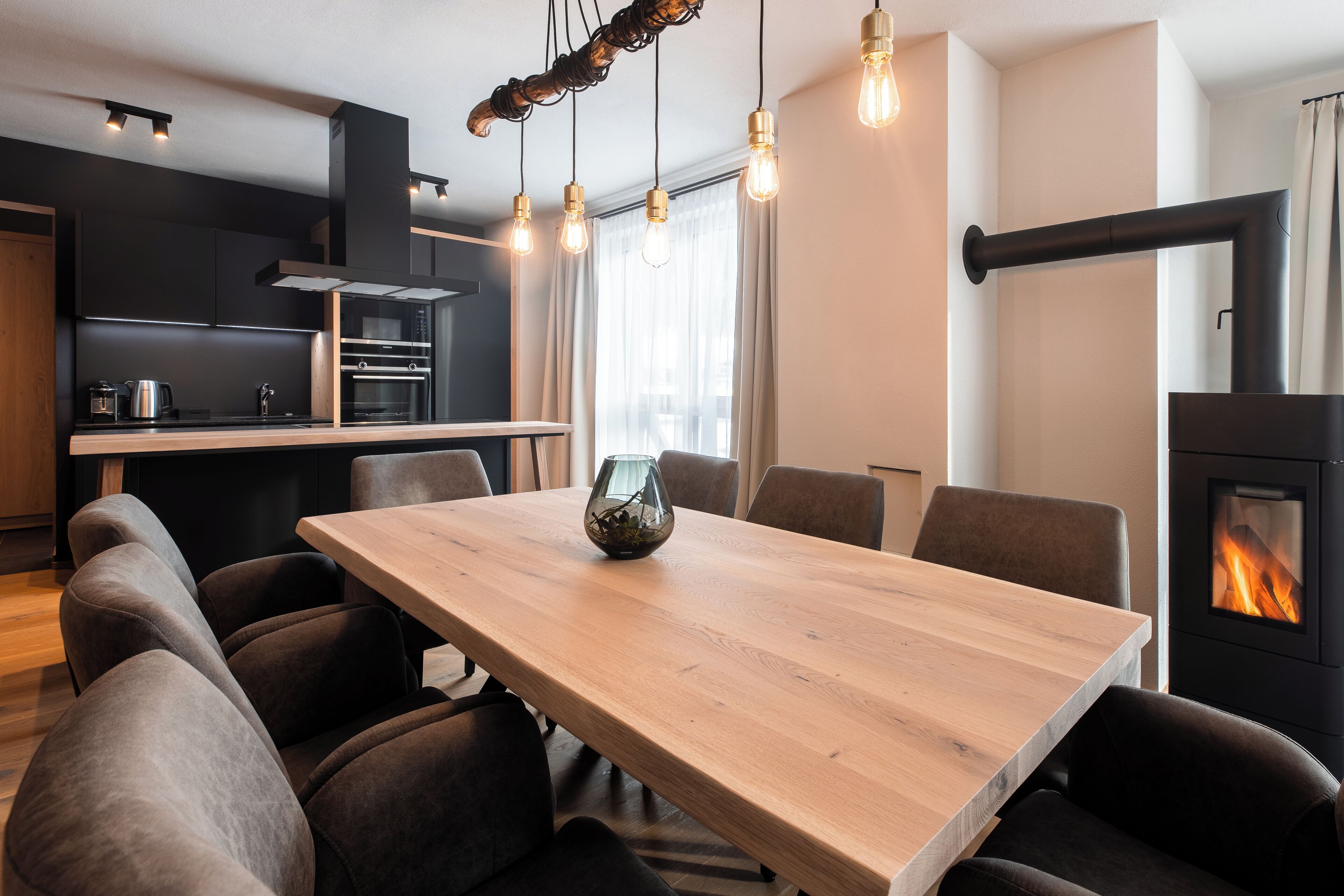 A modern kitchen with a dining area, including a wooden table, chairs, and a fireplace.
