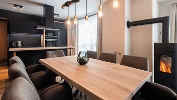 A modern kitchen with a dining area, including a wooden table, chairs, and a fireplace.