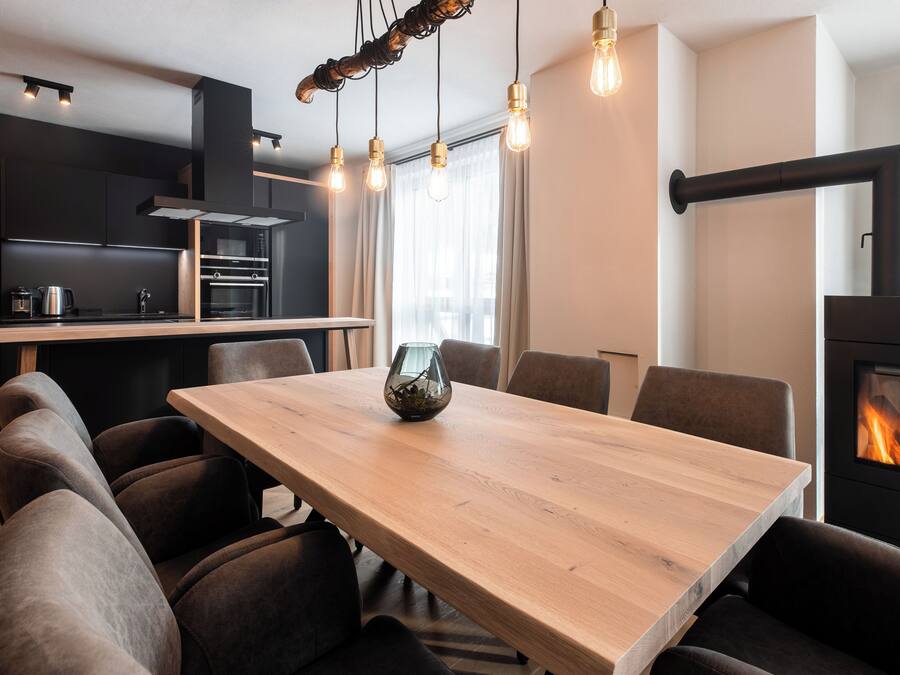 A modern kitchen with a dining area, including a wooden table, chairs, and a fireplace.
