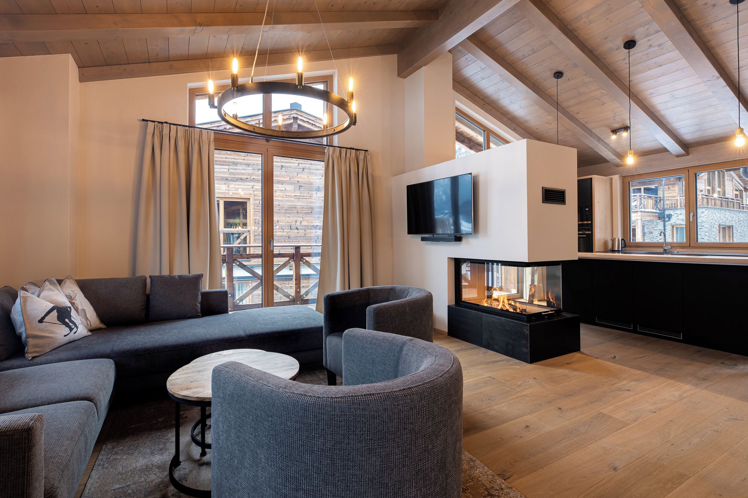 A modern living room with a sofa, armchairs, a fireplace, and a TV on the wall.