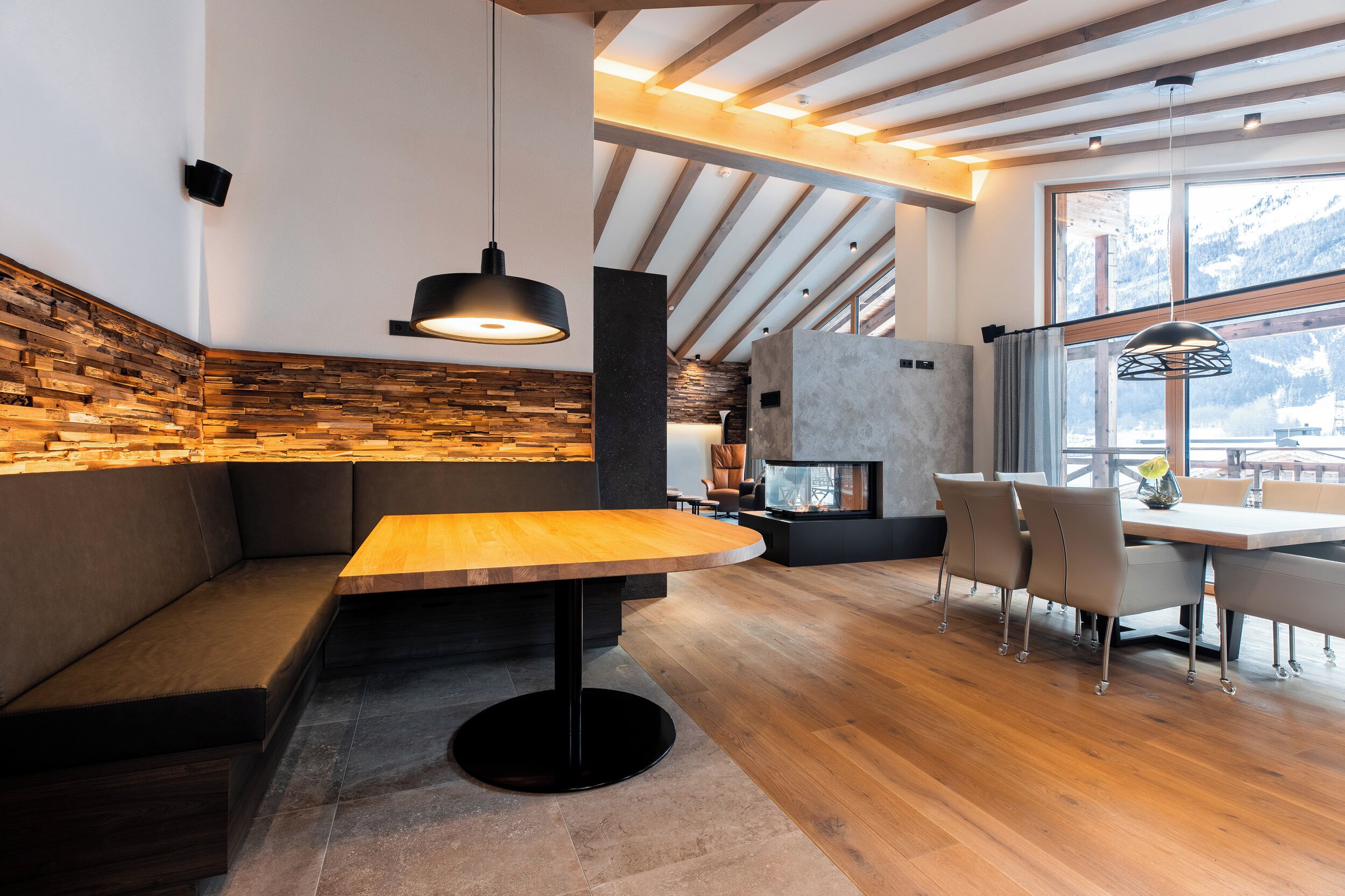 Ein modernes Interieur mit einer hölzernen Bank, einem runden Tisch und einem Essbereich mit Stühlen.